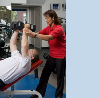 Photo of a PTP personal trainer helping a client with an exercise doing dumbell flyes on an inclined bench.