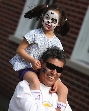 Girl child on her dad's shoulders at a past Buddy Walk for Down syndrome event.