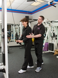 a personal trainer assisting a client with a triceps lat pulldown exercise