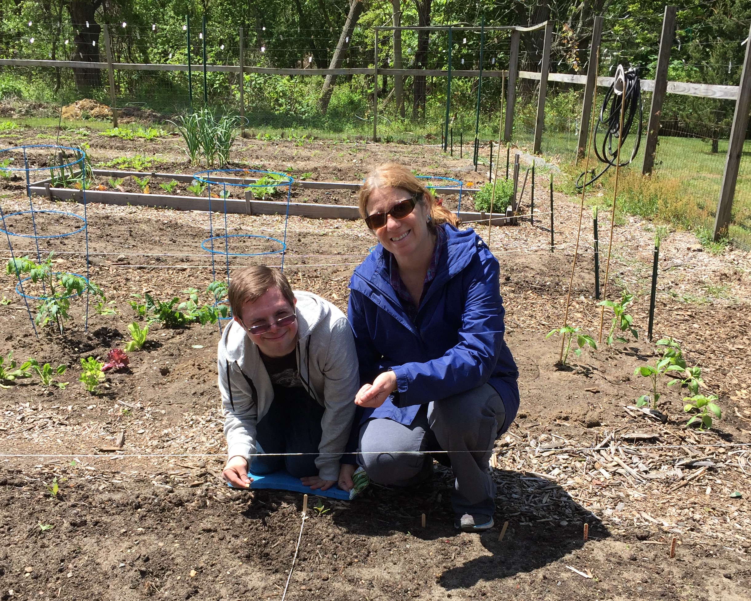 Two people tend plants in the garden.