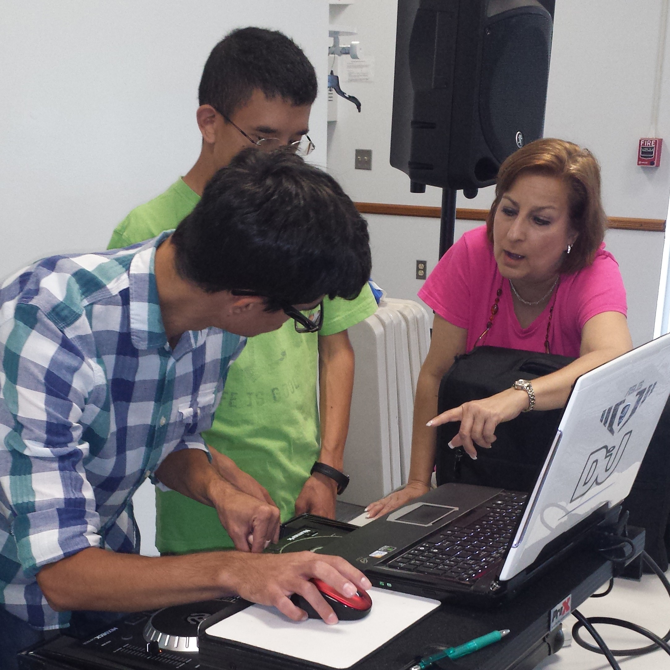 DJ Randi explains to two students how to use the DJ equipment