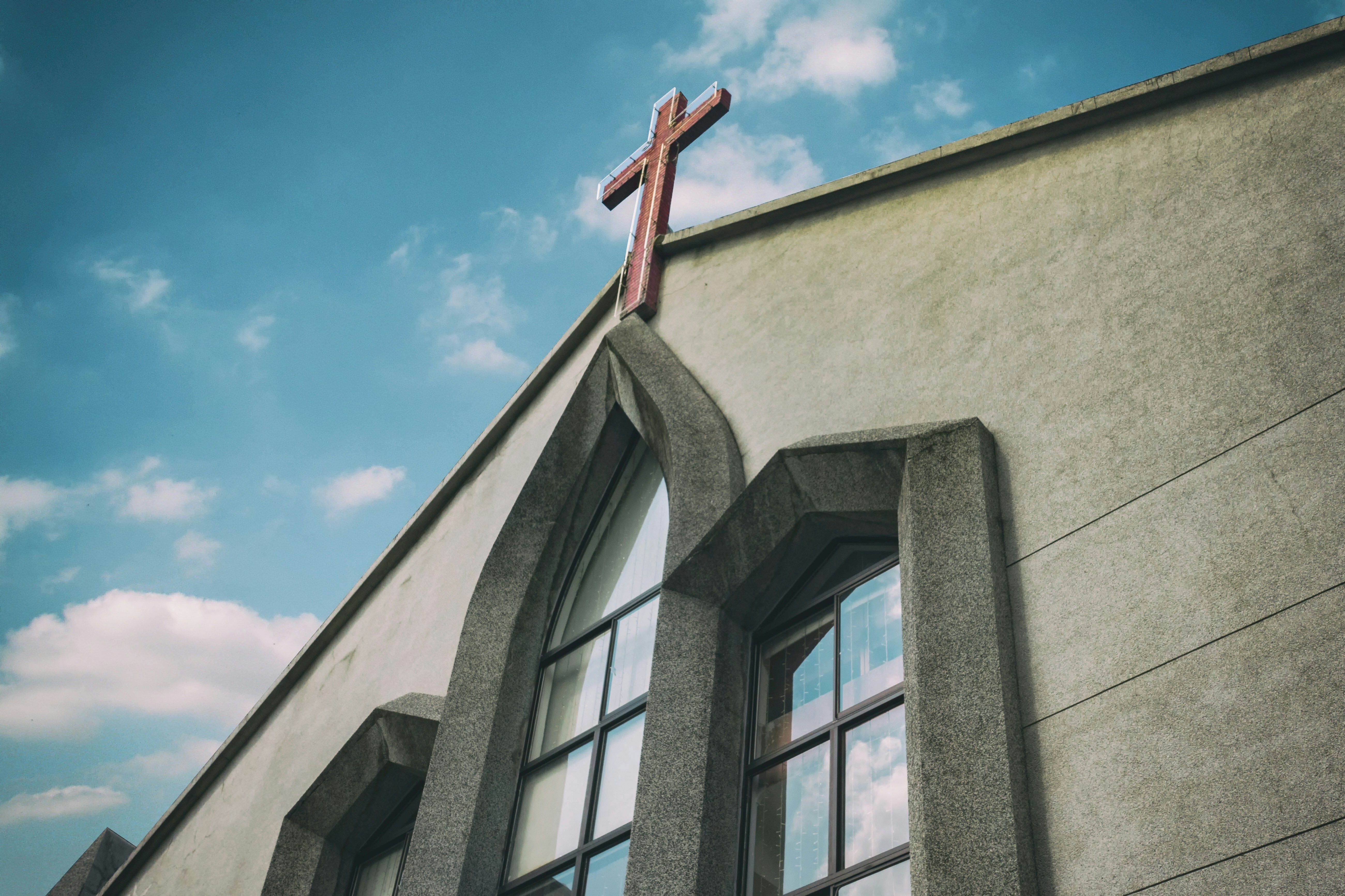 Exterior view of church with large windows and cross