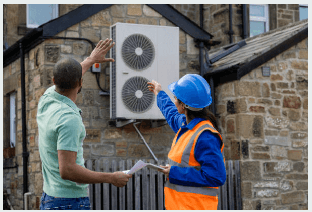 Two people pointing at utility functions outside of a brick building.