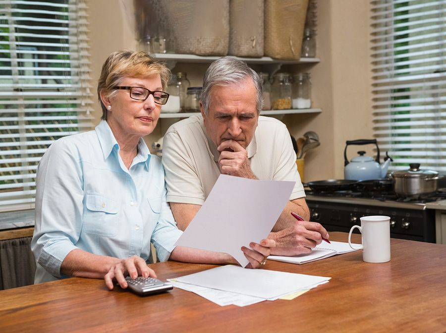Older heterosexual couple sitting at the kitchen table reviewing important paperwork