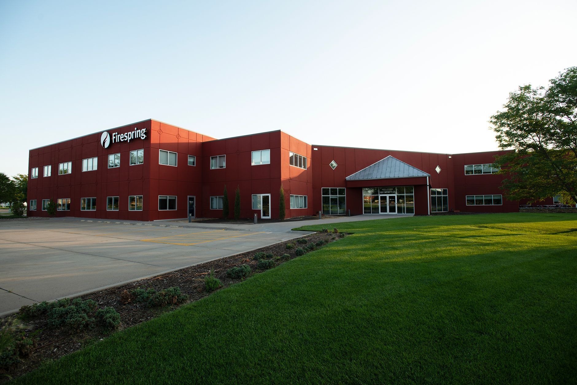 Exterior of a red building with a large white Firespring logo at dusk.