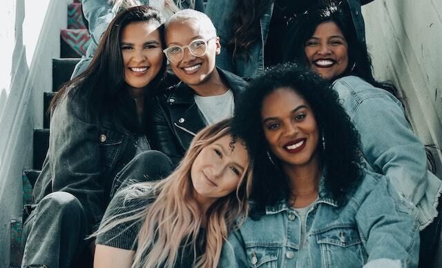 Diverse women sitting together and smiling while seated on stairs