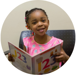 A child smiling while holding a book.