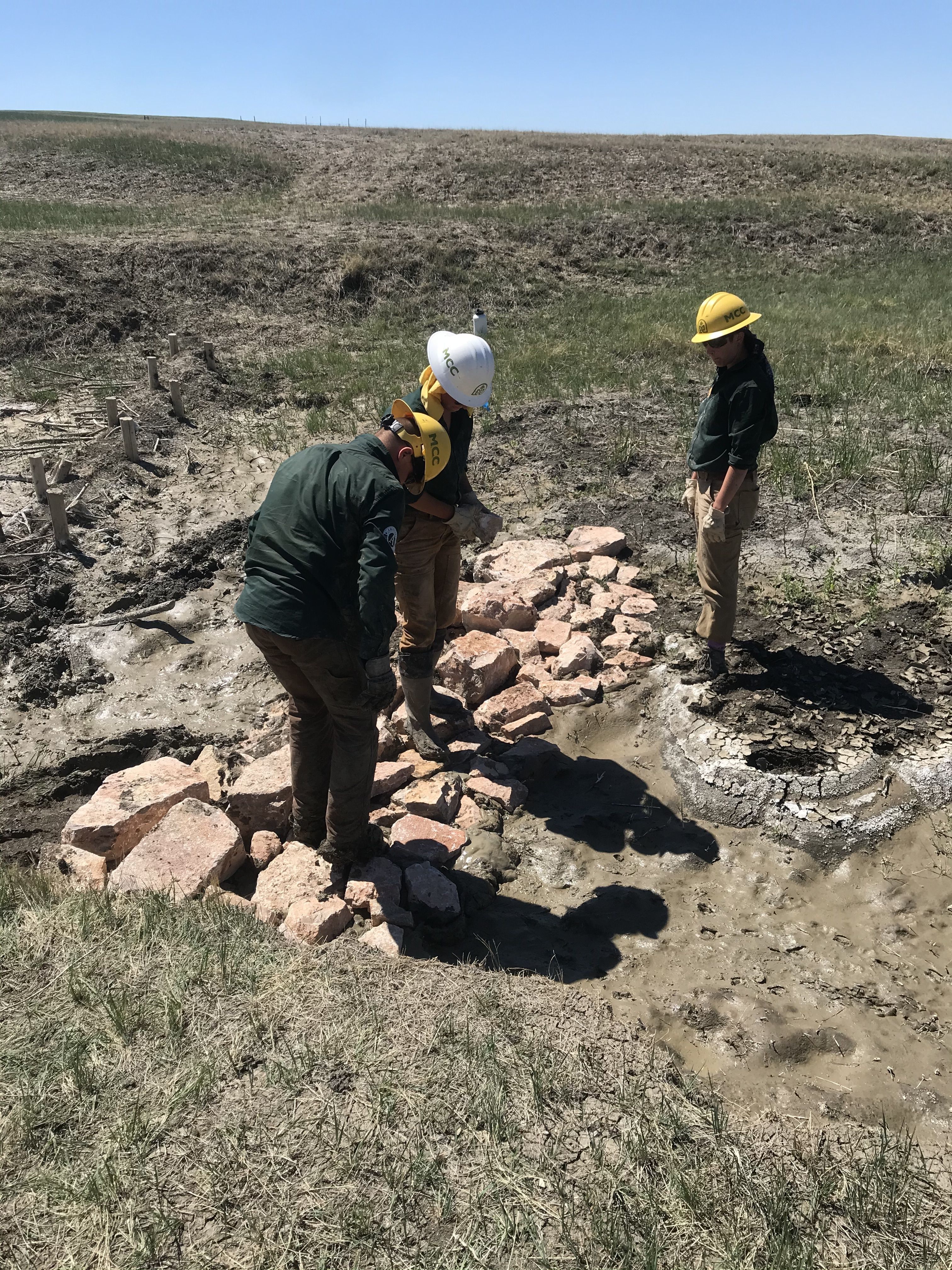 Crew members build a rock beaver mimicry dam