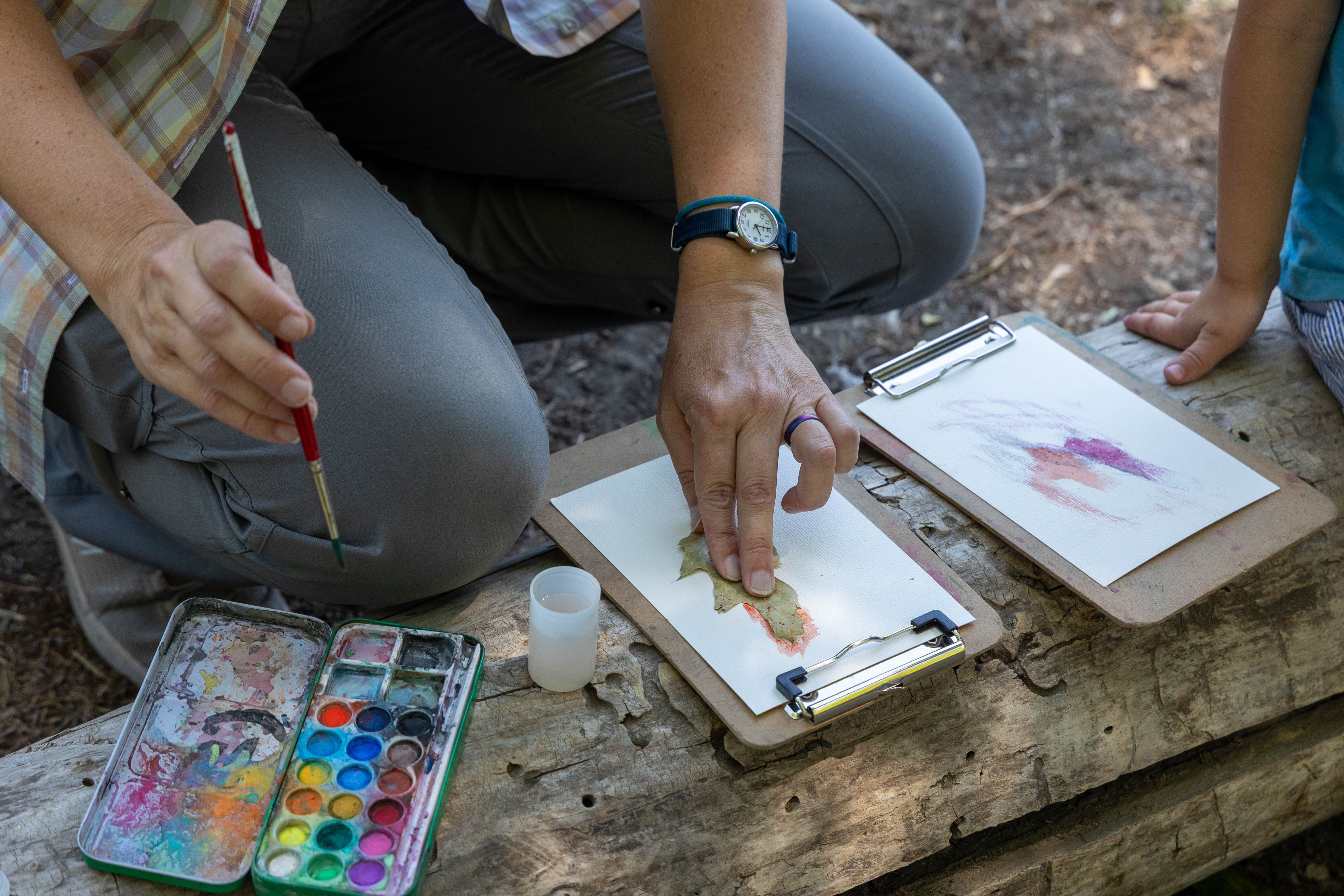 Wenatchee River Institute's Art Walk. The leader traces leaves with water color paints as a kid watches for inspiration. 