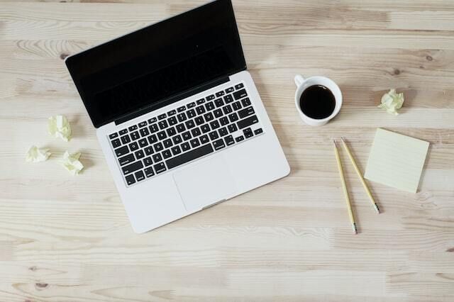 Photo of laptop with coffee, pencil, and notepad