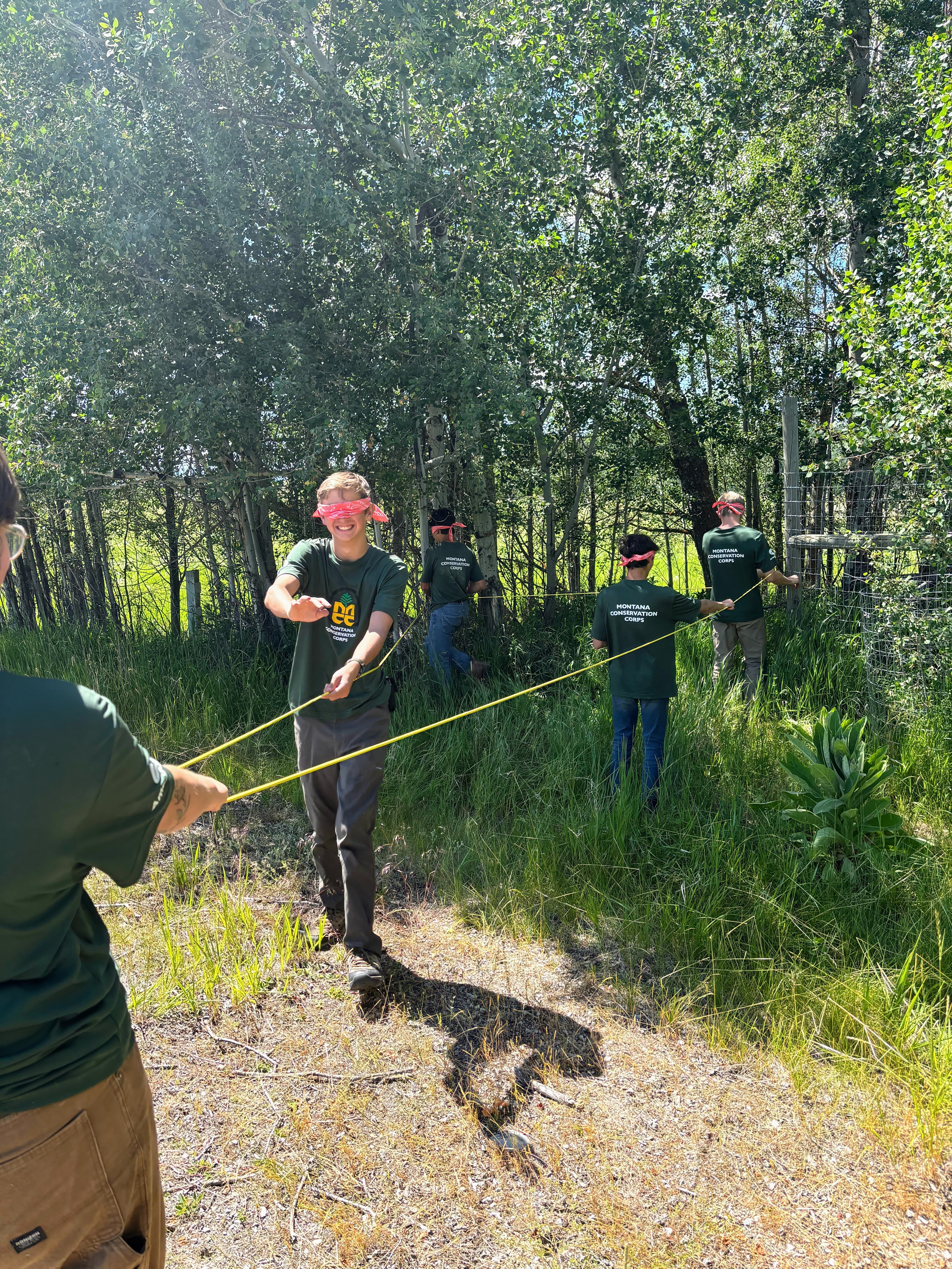 A youth crew plays a game where they navigate along rope with blindfolds on.