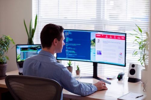 view over the shoulder of man working on desktop computer.