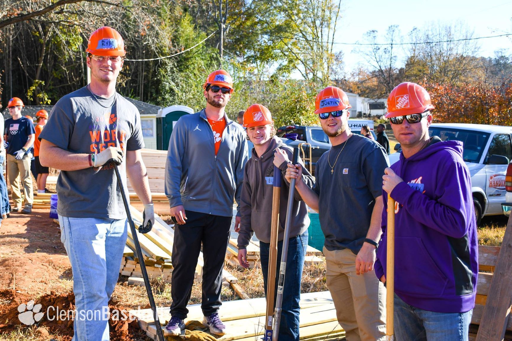 Clemson University baseball players pose in orange hard hats. 