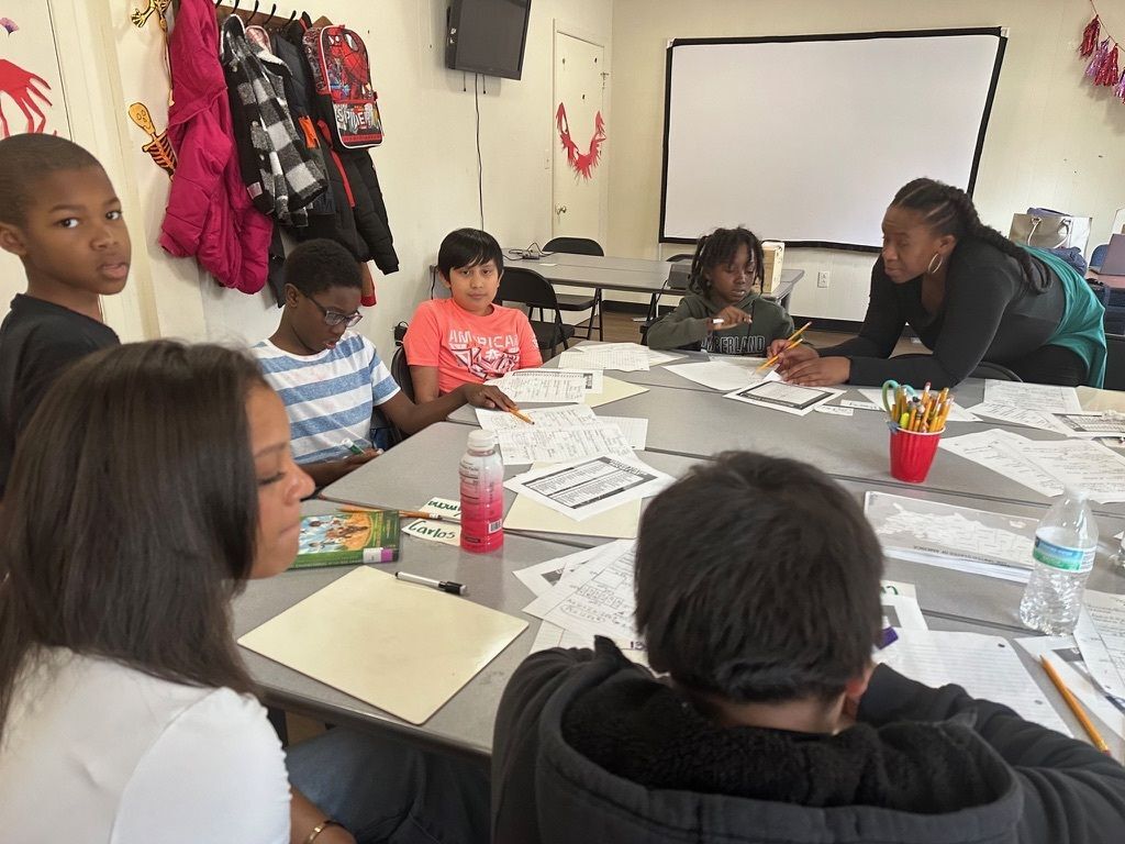 Teacher helping students doing group work at a table.