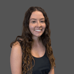 Brunette female with long curly hair. She is wearing a black jumpsuit