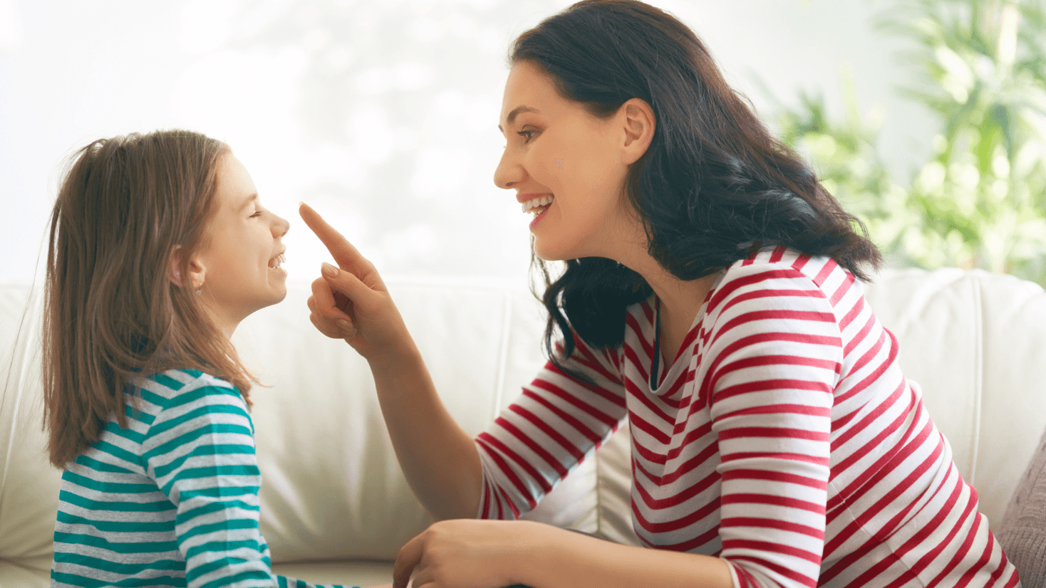 Image of a woman playfully putting her finger on a child's nose