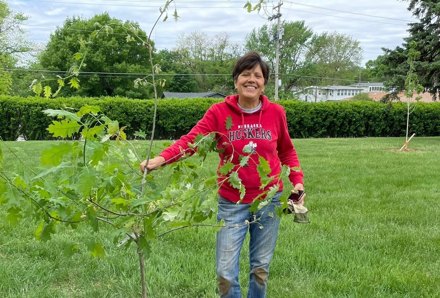 Jane stands by a tree planted at Royale Oaks from a grant provided by Men's Garden Club 