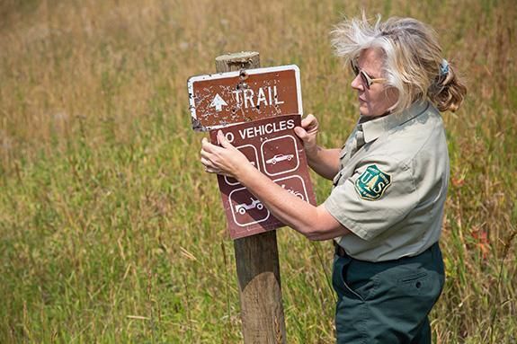 Former USFS employee Mary Erickson adjusts a sign.