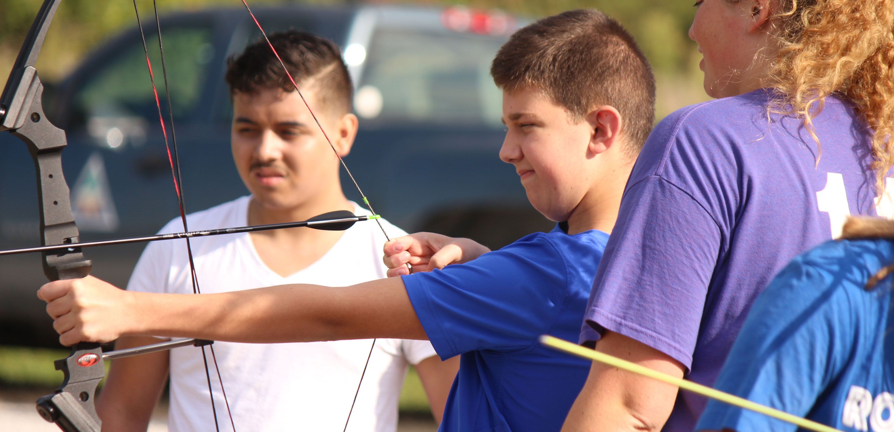 Young boy learning to shoot arrow