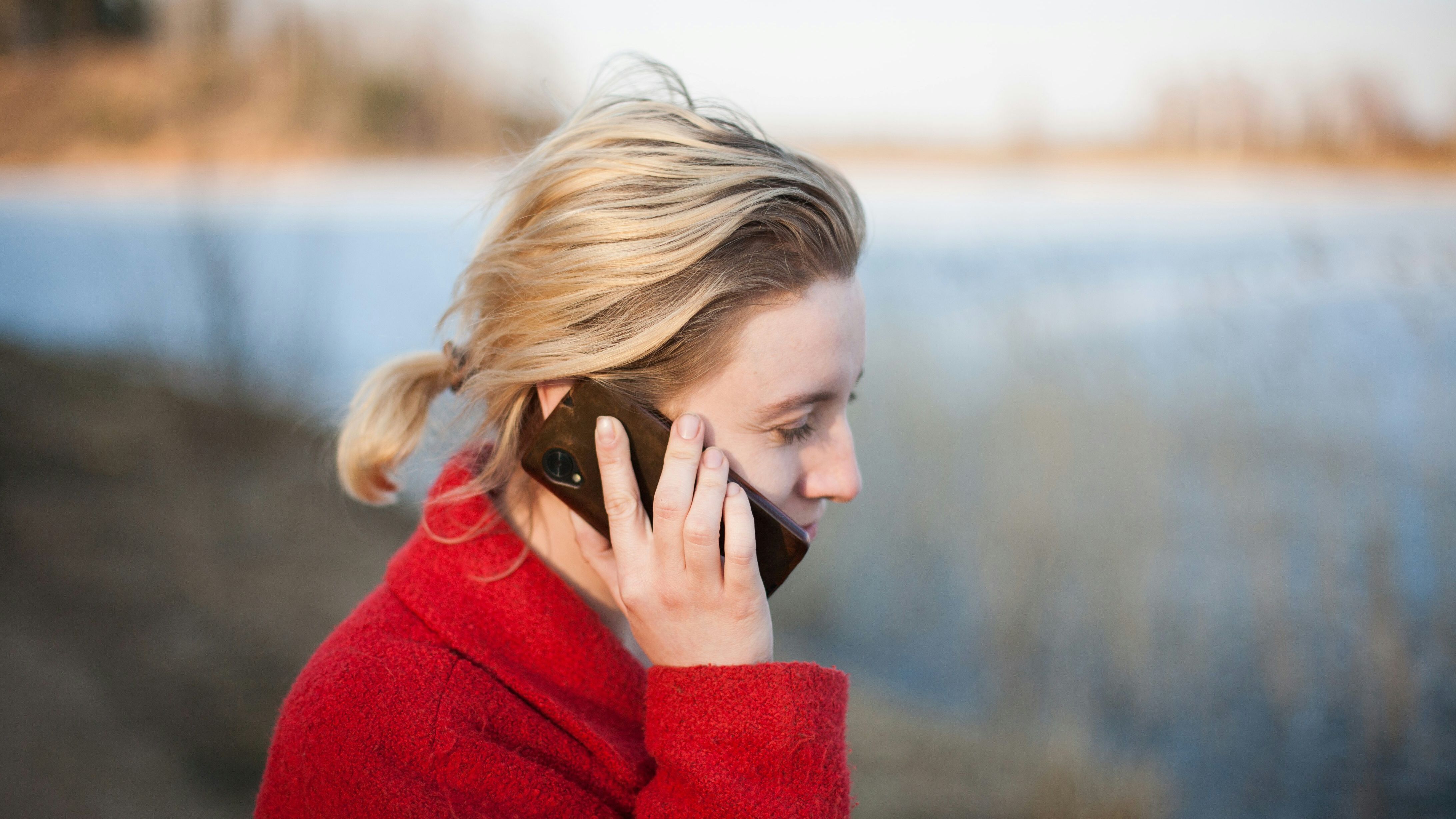 Woman in red coat talks on a cell phone