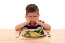 This is a picture of a boy who is unhappy about having to eat his vegetables