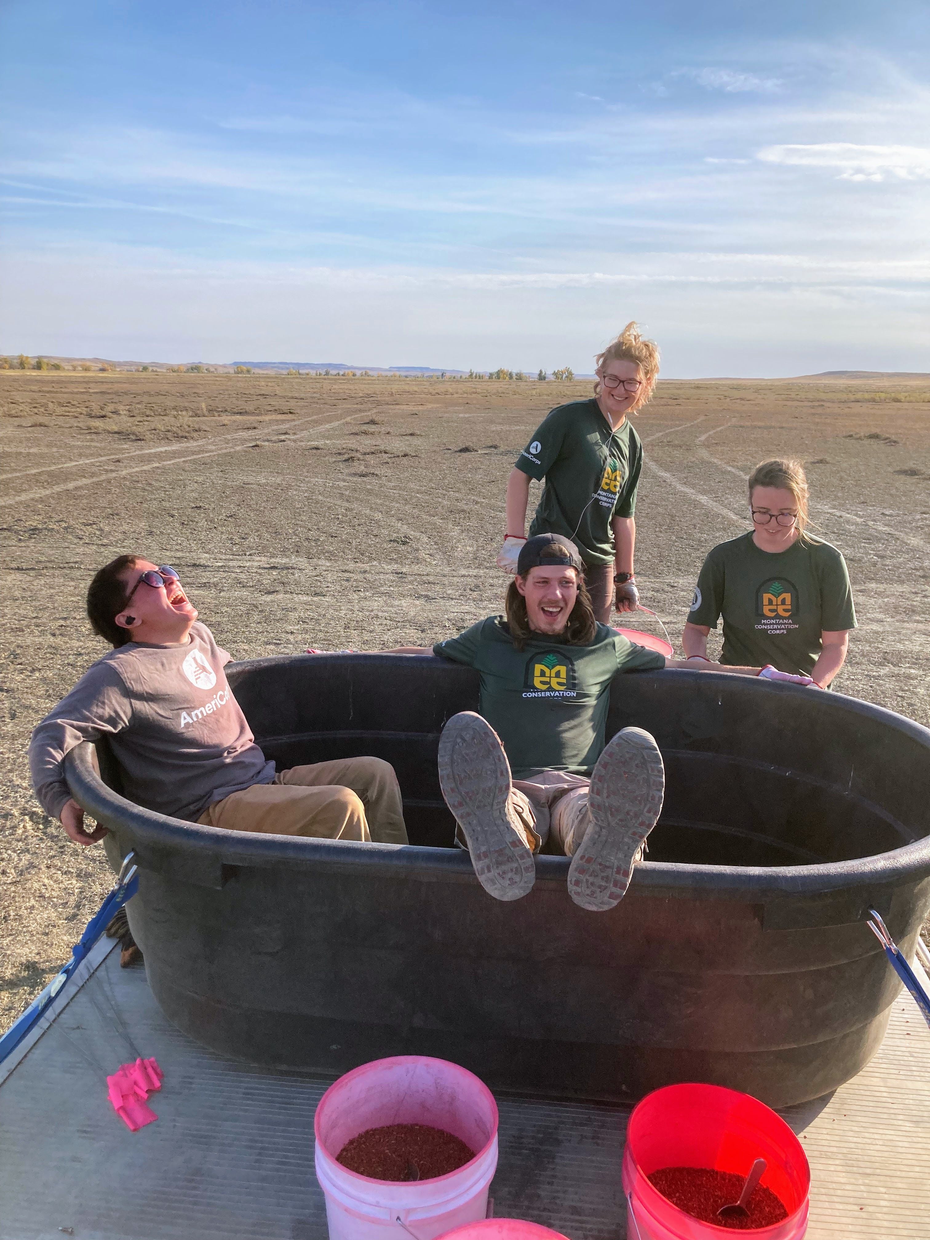 Crew members gather around a large tub in a prairie field