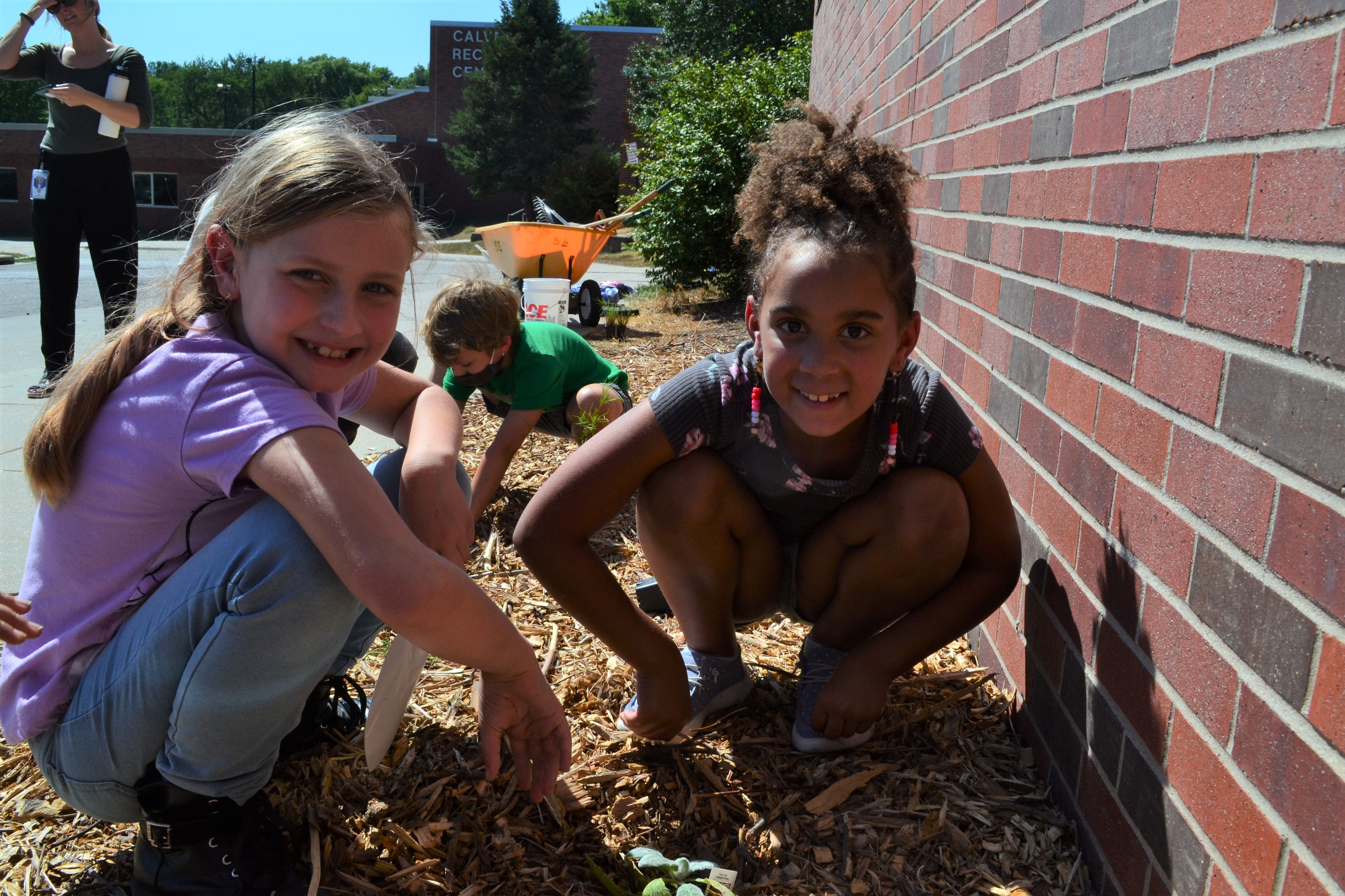 Two elementary school girls plant flowers outside Calvert Elementary in Lincoln, Nebraska. 