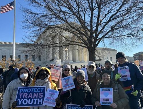 A group of Quakers standing in a crowd in front of the U.S. Supreme Court holding signs that say "Worship in Silence, Love Out Loud" and "Quakers Heart Trans Kids"