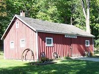 Blacksmith shop building painted red with trees in the background.