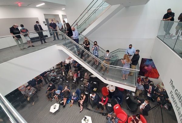 From a second floor vantage point, a crowd gathers on the first floor and atrium stairs of the John and Mary Alford Center for Science and technology.