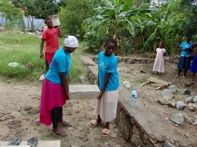 Two woman carrying cement block.