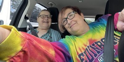 A selfie of Amy and Beth in the front seats of a car.  You can see Beth's arms as she holds the phone's camera out.