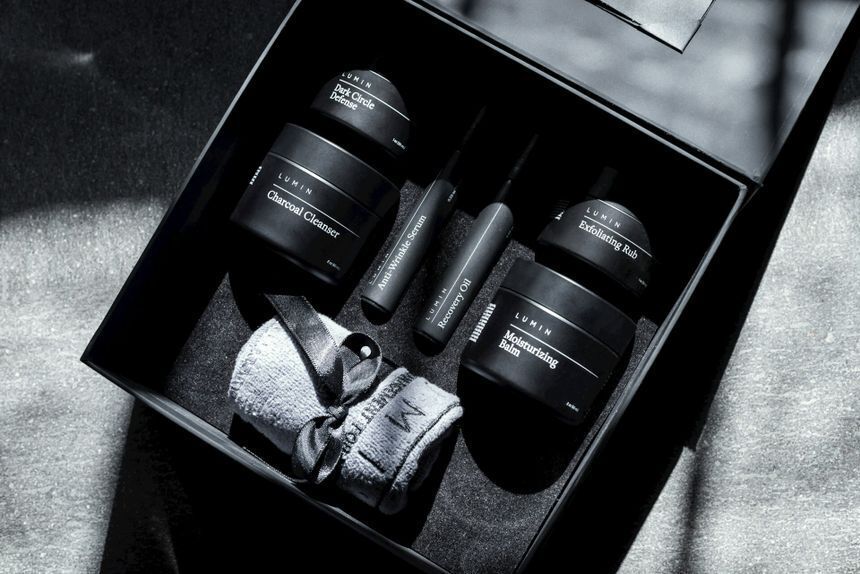 Premium black e-commerce packaging box utilizing custom structural inserts to display men's skincare products and a rolled towel
