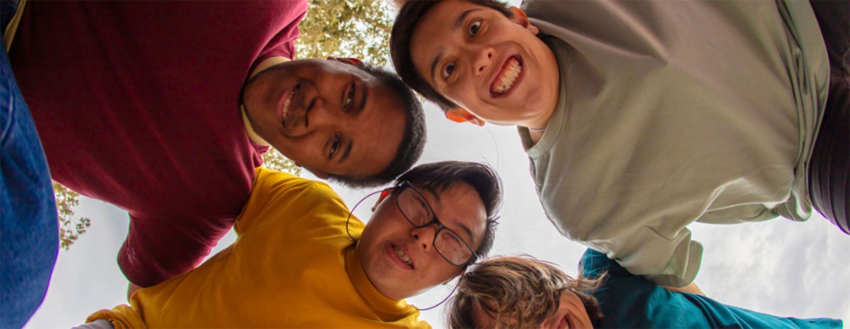 Five people leaning over and smiling at the camera, forming a circle.