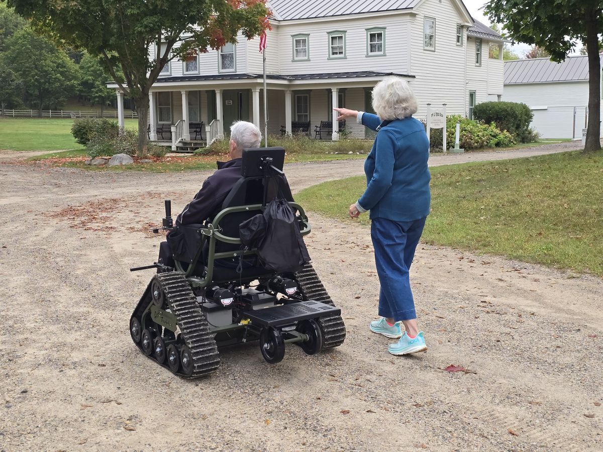 Person using the track chair and another pointing the way. 
