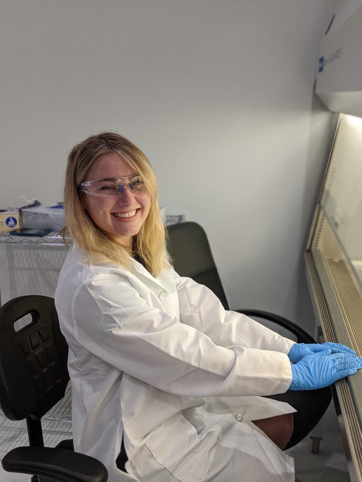Student wearing lab coat smiles at camera