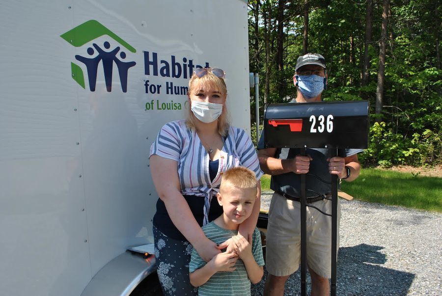 Mother and her son standing next to a man holding their mailbox.