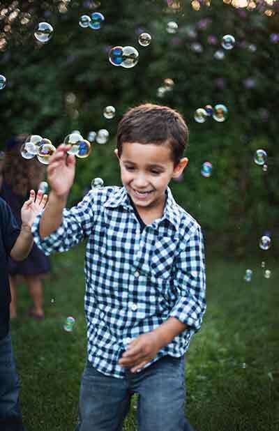 Child popping bubbles outside and smiling
