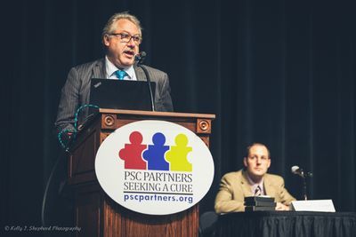 A researcher is speaking at the basics of PSC while standing at a PSC Partners podium.