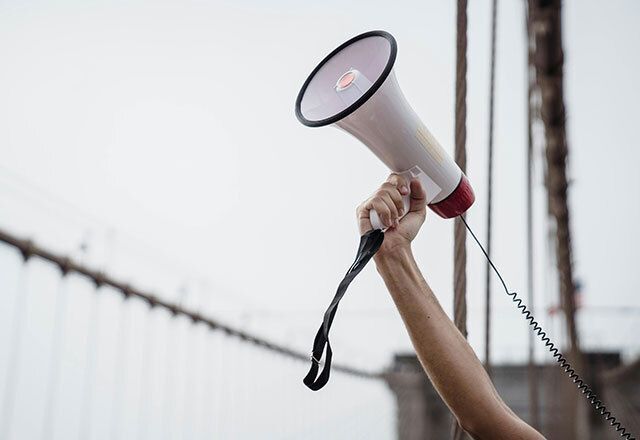 Hand holding a megaphone to the sky.