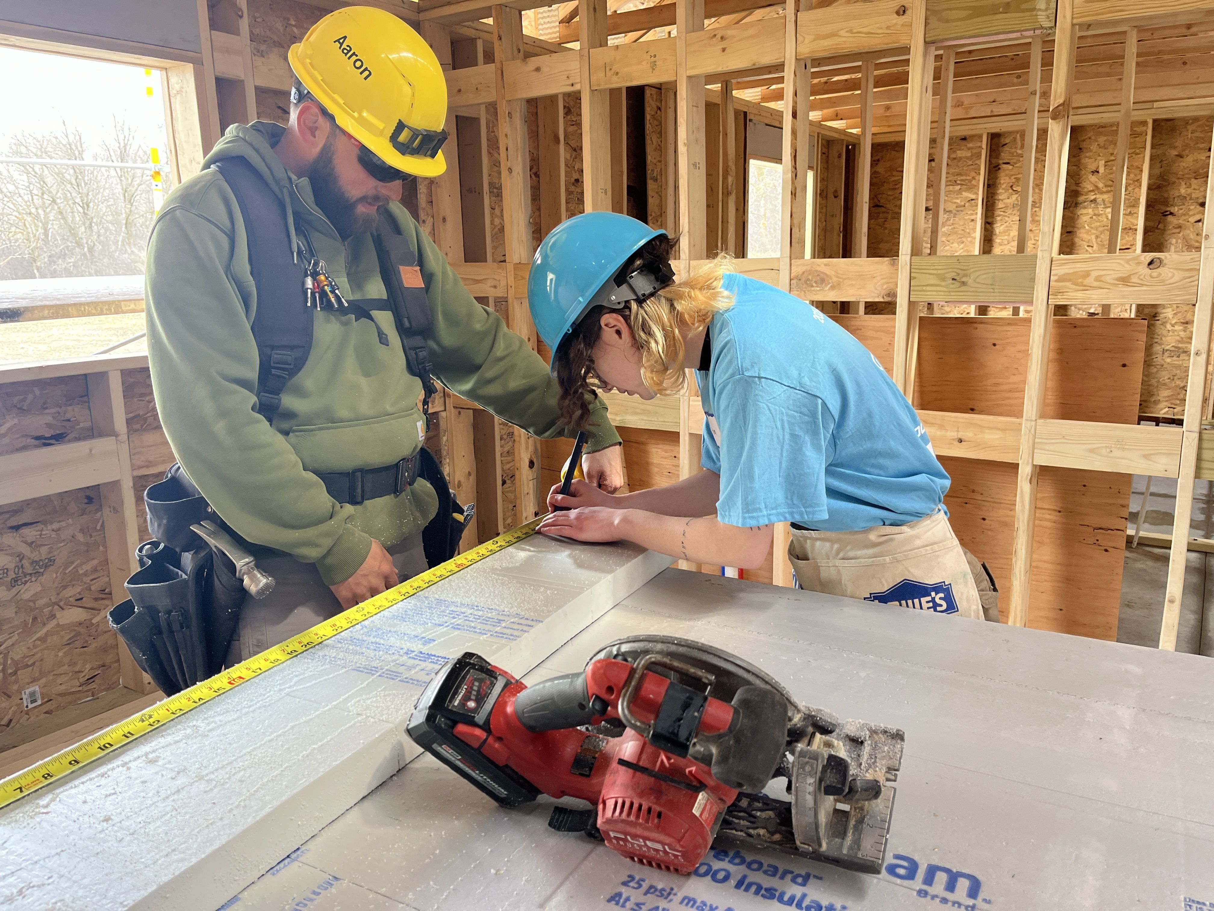 construction team teaching volunteer to measure