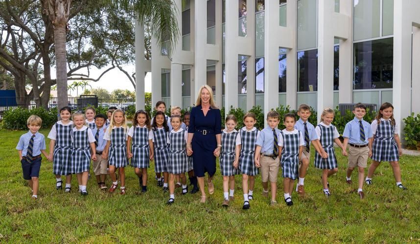 Rachel Polak, principle of St. Clare School in North Palm Beach, poses for a photo with students outside of the newly renovated school.