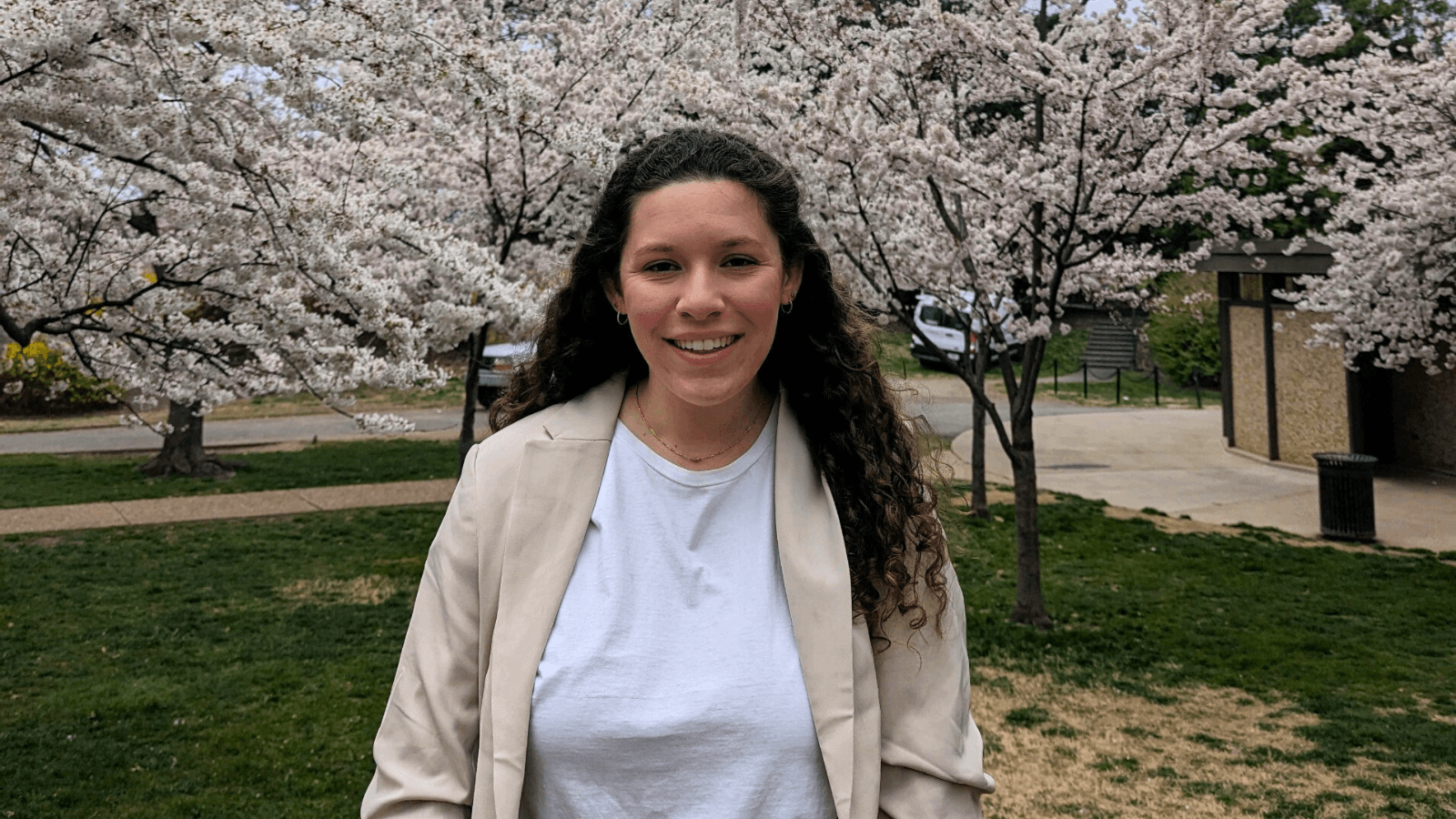 Jaime standing in front of blossoming cherry trees in Washington, D.C.