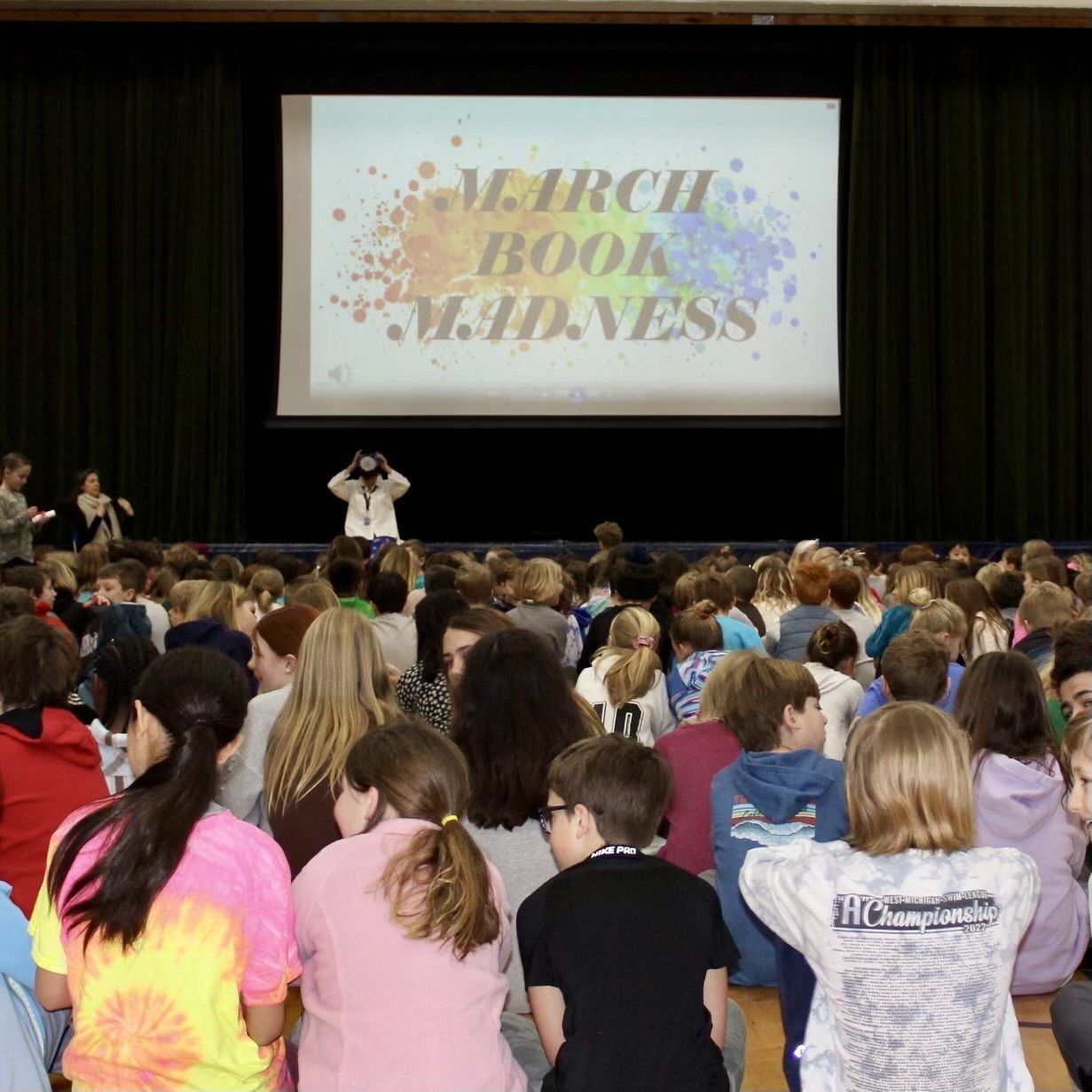 photo of kids in gym by March Book Madness sign