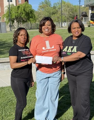 three women holding grant check smiling