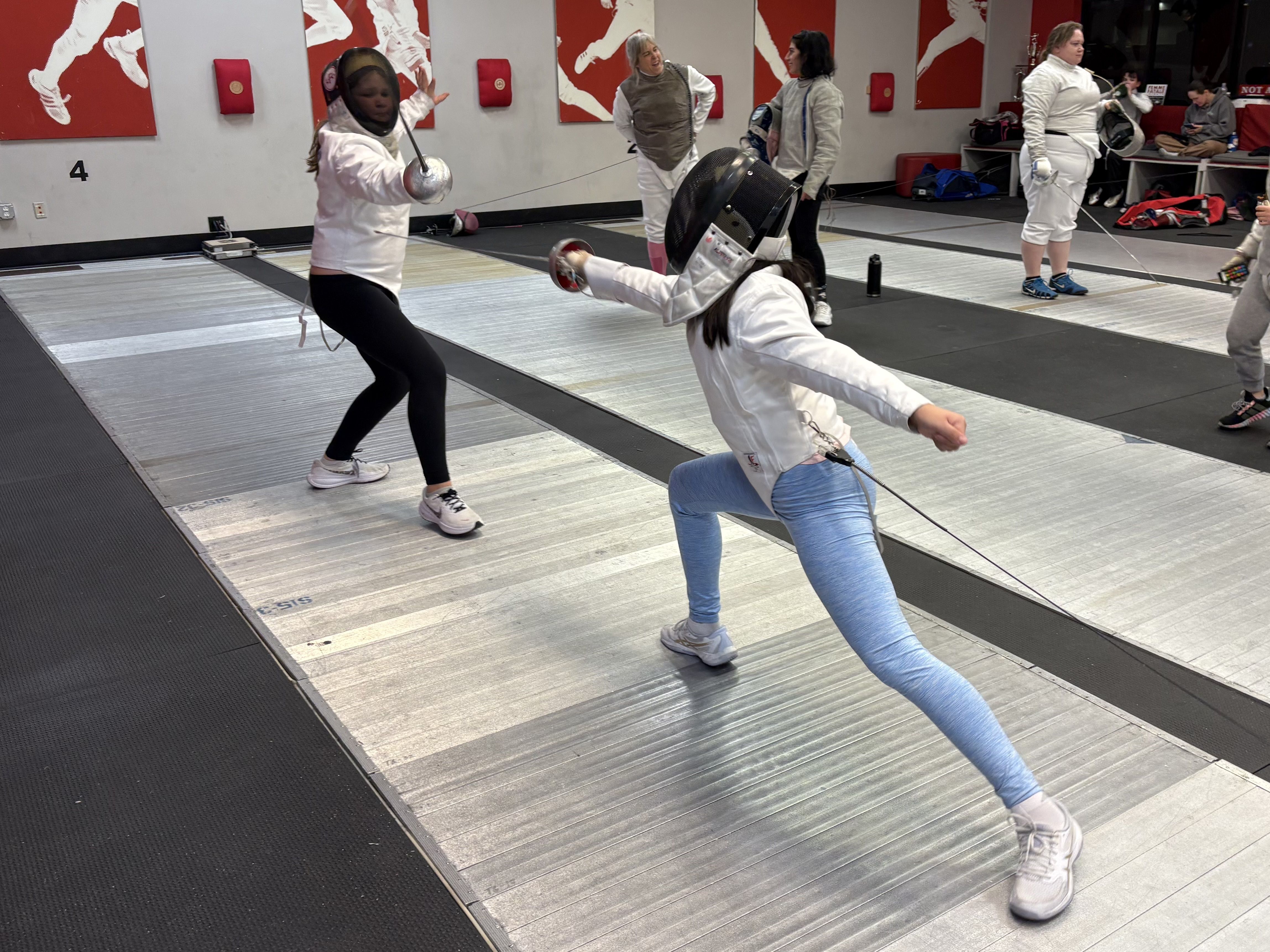 A youth fencer lunges at her opponent