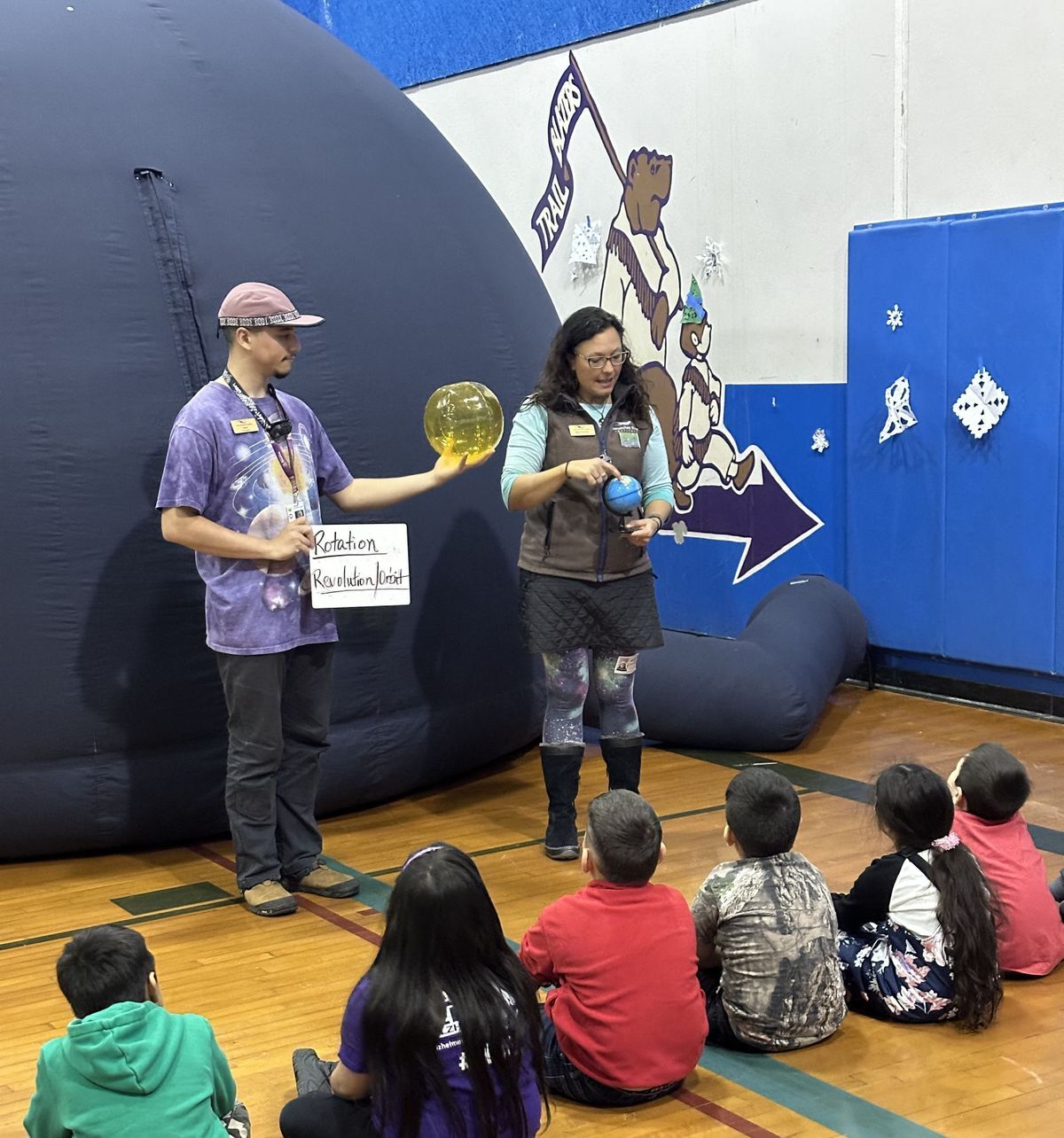 Two educators instructing students on a space lesson before entering the planetarium.