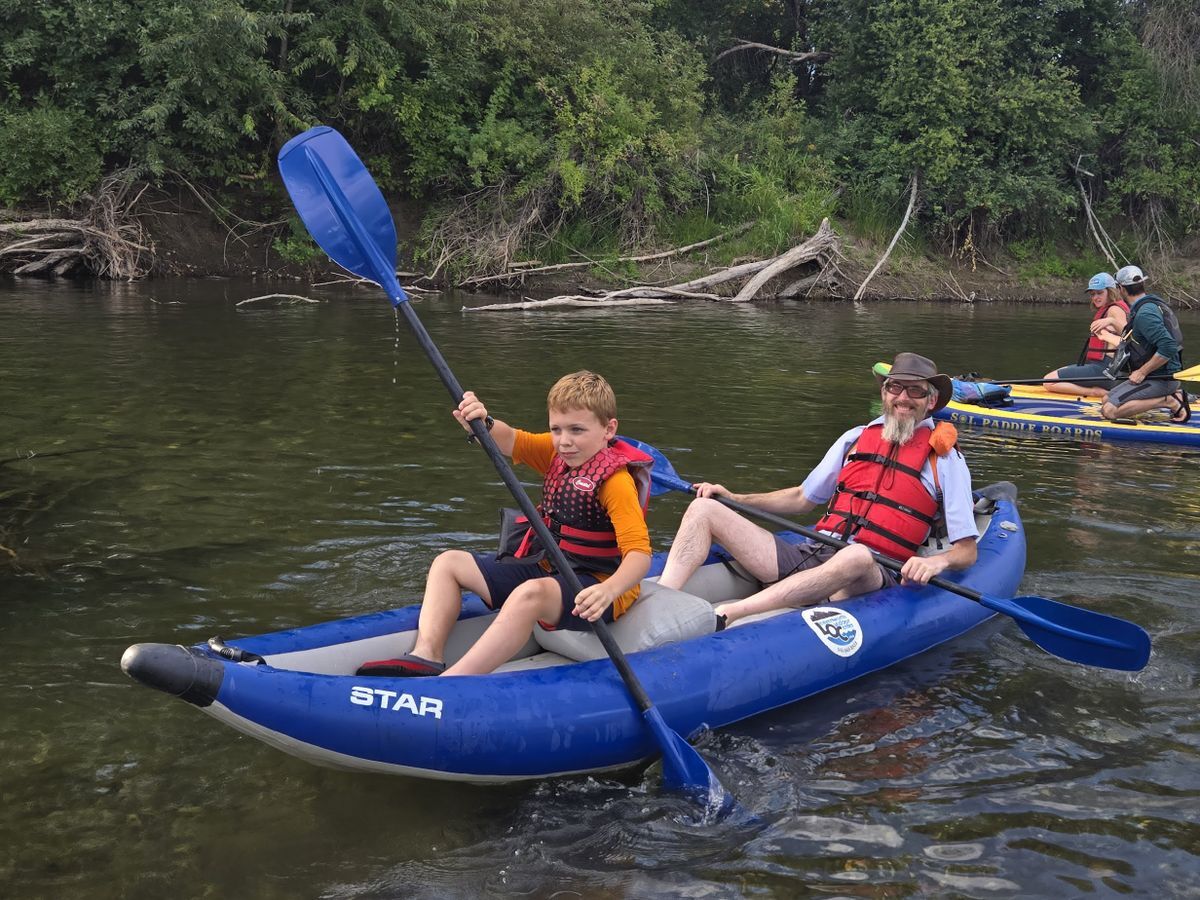 A father and son sharing a kayak paddle during a River Discovery Tour.