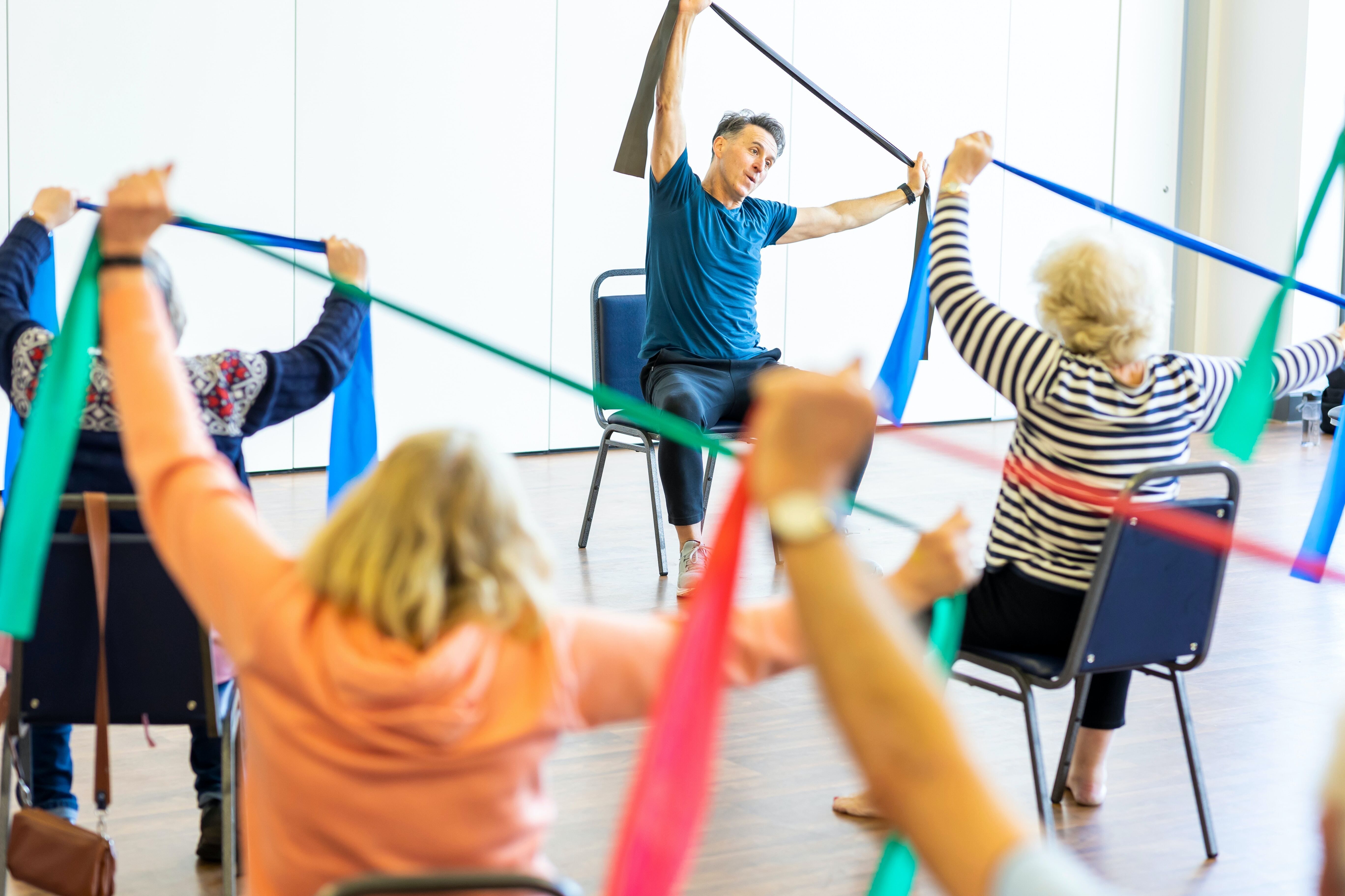 older adults sitting using resistance bands to exercise 