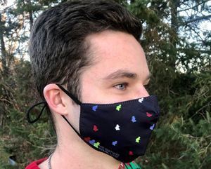 This shows a young adult male wearing a PSC Partners mask, which is black with colorful puzzle pieces on it.